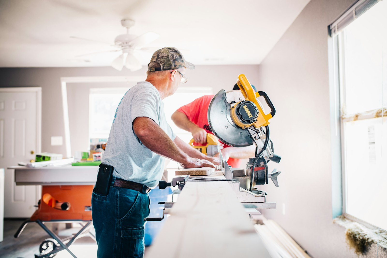 Two tradesmen cutting timber at a mitre saw in a house being renovated
